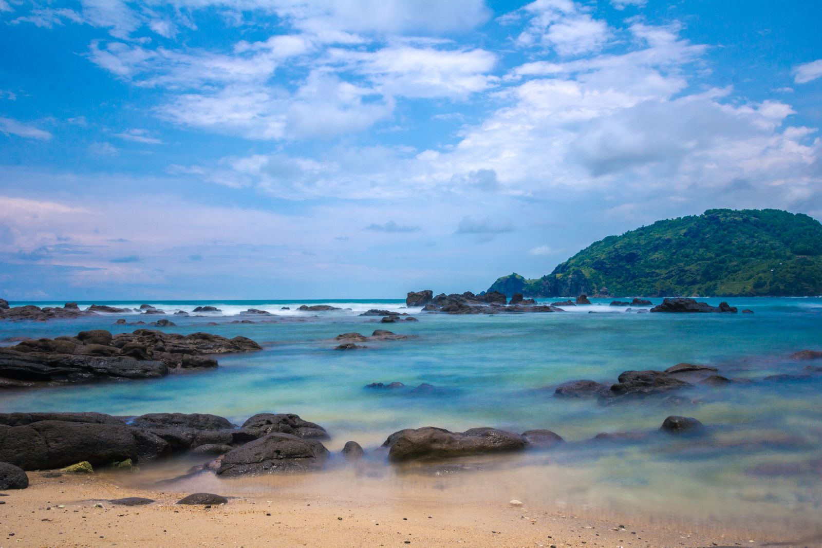 A green headland meeting the sea in a rocky Caribbean bay